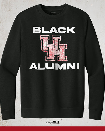 Image of a black "Black UH Alumni Crewneck Sweatshirt" with bold, white text reading "BLACK ALUMNI" surrounding a speckled red "UH" logo in the center. The design highlights pride and unity for Black Alumni of the University of Houston, presented on a modern and stylish garment perfect for showing school spirit.